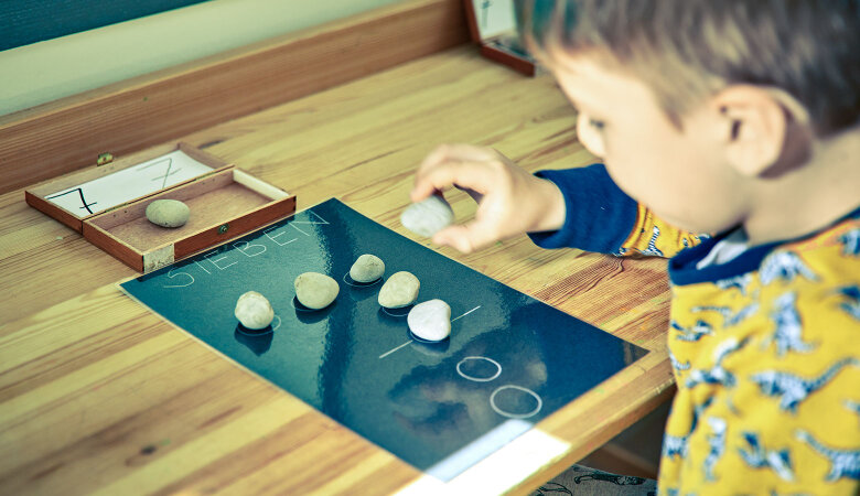 Szene im Kindergarten: Junge legt Steine in Form einer Sieben.